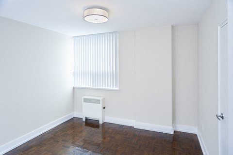 a living room with white walls and a window and wooden floors